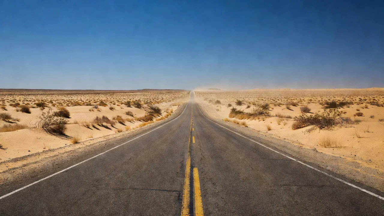 A long desert highway vanishing toward the horizon at midday