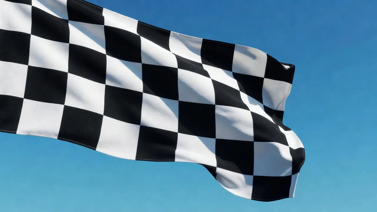 A chequered racing flag waving against a bright blue sky