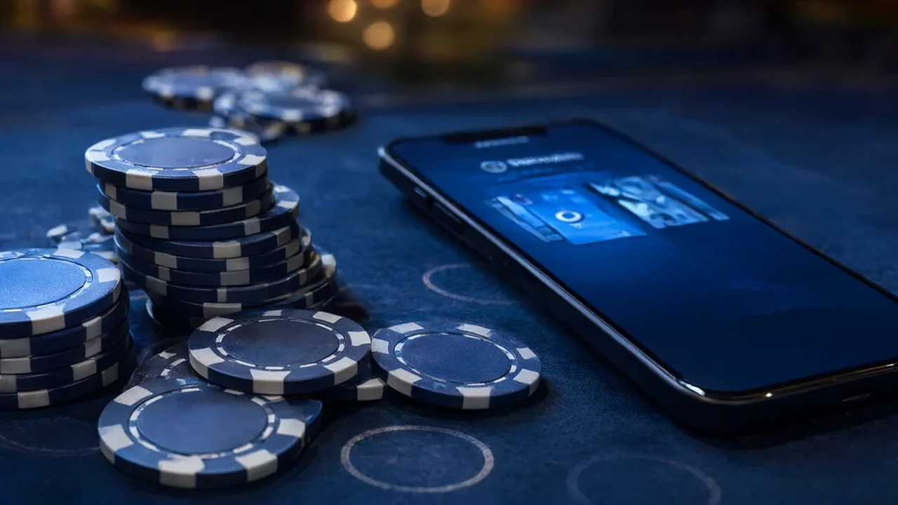 Casino chips and a smartphone showing a cashback balance on a dark table